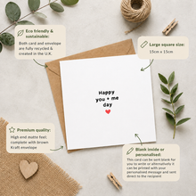A white anniversary card with the words 'Happy you + me day' and a small red heart, shown with a brown kraft envelope on a neutral textured background. Decorative leaves, twine, and wooden clothespins surround the card, with callout boxes providing product information about sustainability, size, envelope, and personalization.