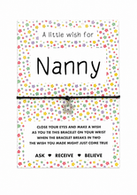 Nanny wish string bracelet. A rectangular card with a colourful floral border and the word 'Nanny' in large black text, wrapped with a black cord bracelet around the centre. A small silver star charm hangs from the black cord.