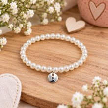Personalised pearl bracelet with initial. A pearl beaded bracelet with a silver round charm engraved with the letter 'E'. Customised Pearl bracelet 