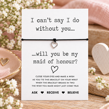 Maid of honour wish string bracelet. A white display card with black text reading 'I can't say I do without you. Will you be my maid of honour? With a silver heart charm bracelet.