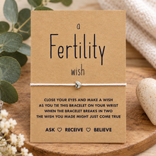 Fertility wish string bracelet. White cotton cord bracelet with small silver heart bead charm. Displayed on the A LITTLE WISH FOR FERTILITY keepsake card with wish instructions. 