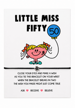 A white rectangular card with the text 'LITTLE MISS FIFTY' and a wish bracelet with star attached 