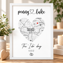 A framed personalised wedding map print on a white background, featuring a heart-shaped map of Newcastle upon Tyne with the names 'penny' and 'luke' at the top and 'The 'I do' day' with a date below.