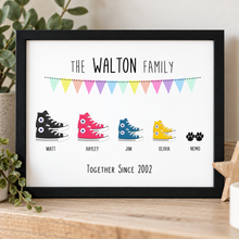 A framed personalised family trainers print on a , featuring the text 'THE WALTON FAMILY' and 'TOGETHER SINCE 2002' with colourful high-top shoe illustrations labeled for family members and black paw prints.
