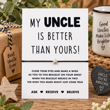 Uncle wish string bracelet. A white rectangular card with black text reading 'MY UNCLE IS BETTER THAN YOURS!' Attached to the card is A black bracelet with a small star is shown as the product.