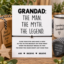 A white wish string bracelet with black text reading 'GRANDAD: THE MAN. THE MYTH. Silver star charm on a black cotton cord bracelet.