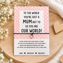 Mum wish string bracelet. A square pink card with white hearts and black text tied with a black cord bracelet and a small heart charm, with wish instructions.