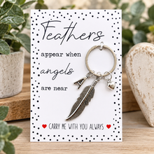 Personalised Bereavement sympathy key ring.Silver feather keychain with an 'A' initial charm and small heart charm, displayed on a white memorial card that reads 'Feathers appear when angels are near' and 'Carry Me With You Always'.