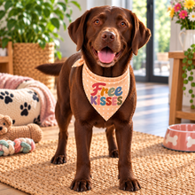A chocolate Labrador retriever wearing a peach polka dot bandana with the words 'Free KISSES' in colourful letters. Patterned Dog neck tie
