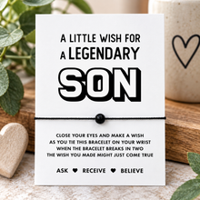 Son wish string bracelet. A white display card with bold black text reading 'A LITTLE WISH FOR A LEGENDARY SON' and instructions below, tied with a black cord and black bead.