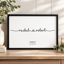 A framed personalised engagement print with the names 'rachel' and 'robert' connected by a small heart. Joined up names engagement print.