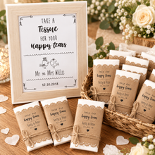 Personalised wedding favours including a large framed sign reading 'Take a Tissue for Your Happy Tears' with wedding names and date, plus wrapped wedding tissues. The wraps are white with Kraft brown sleeves with lace trim and tied with twine.