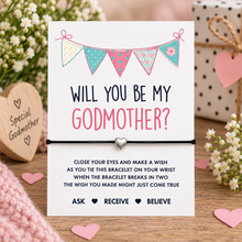 Godmother wish string bracelet. Black cotton cord bracelet with small silver heart bead charm. Displayed on the Godmother proposal  keepsake card with wish instructions. Will you be my Godmother gift.