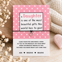 A pink and white polka dot card with a message for a daughter, tied with a black cord bracelet with a small heart charm. Daughter wish string bracelet 