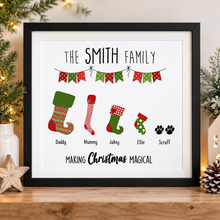 A framed personalised Christmas art print. The print features the text 'THE SMITH FAMILY' and 'MAKING Christmas MAGICAL' with illustrated Christmas stockings labeled for family members: Daddy, Mummy, Jakey, Ellie, and Scraft. Family Christmas gift 