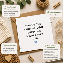 A white greeting card with black text reading 'YOU'RE THE KIND OF DAD EVERYONE WISHES THEY HAD' and a small blue heart, shown with a kraft envelope on a styled flat-lay background. Surrounding props include dried flowers, twine, wood clips, a knit fabric, and informational callout boxes describing eco-friendly sustainability, large square size 15cm x 15cm, premium matte feel, and personalization options.