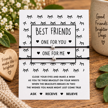 Matching Best friends wish string bracelets. A white card with black text and eyelash illustrations holds two thin black bracelet cords with small silver star charms. The card reads 'BEST FRIENDS ONE FOR YOU ONE FOR ME' and includes a wish-writing instruction.