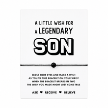 A white rectangular card with black text reading 'A LITTLE WISH FOR A LEGENDARY SON' and a black cord bracelet with a black bead tied across the centre. Gift for son 