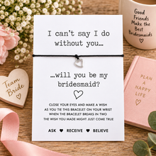 A bridesmaid wish string bracelet. A presentation card featuring a black cord bracelet with a small silver heart charm. Bridesmaid proposal gift. 