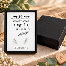 Sterling silver feather stud earrings displayed on a white sign inside a black frame that reads 'Feathers appear when angels are near' and 'STERLING SILVER'. Complete with black gift box.