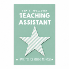 Teaching assistant wildflower seeds gift. A green greeting card with white text reading 'For a brilliant TEACHING ASSISTANT' and 'THANK YOU FOR HELPING ME GROW,' featuring a large striped plantable seeds star in the centre. Gift for teaching assistant. Thank you TA 