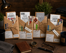 book gift for him with rustic kraft paper envelopes and twine bows are arranged on a wooden table with themed props including a lamp, books, a mug, glasses, and a notebook.