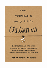 A brown kraft paper card with black printed holiday text reading 'Have yourself a merry little Christmas' and 'Ask Receive Believe,' tied with a black cord bracelet and a small silver star charm, on a white background.