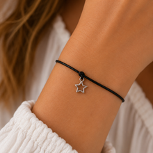 Star wish bracelet. A silver star charm on a black cotton cord bracelet.