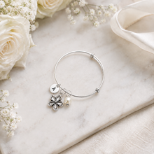 Personalised Thank you for being our flower girl charm bangle. A silver charm bracelet presented in a floral gift box. The bracelet has a round silver bracelet with a flower charm, a small pearl bead, and a round initial charm. Flower girl gift.