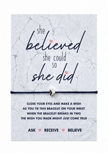 A bracelet gift card featuring the motivational quote 'she believed she could so she did' . A thin black cord with a small silver bead is shown across the centre. New job or starting exams gift. Dance competition present.