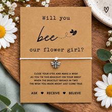 Flower girl proposal wish string bracelet. A kraft card with the text 'Will you bee our flower girl?' and a small bee charm tied with a white string. Flower girl gift 