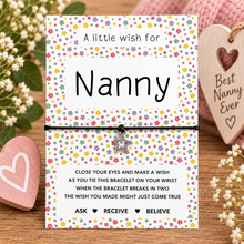 A 'Nanny' bracelet wish string. The presentation card features a colourful floral pattern and a black cotton cord bracelet with a silver star charm. Gift for nanny
