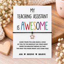 Teaching assistant gift. A black cord bracelet with a small silver star charm displayed on a white message card that reads 'MY TEACHING ASSISTANT IS AWESOME' in colorful lettering.