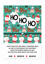A Christmas wish bracelet with the words 'HO HO HO' in large white circles. Below the pattern, the tag includes instructions for making a Christmas wish with a bracelet and the words 'ASK RECEIVE BELIEVE' with heart icons. Stocking filler gift.