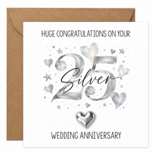 A square silver wedding anniversary card with a kraft brown envelope behind it. The card reads 'HUGE CONGRATULATIONS ON YOUR 25 Silver WEDDING ANNIVERSARY' with watercolor-style silver hearts, stars, and a metallic silver heart keepsake at the bottom.