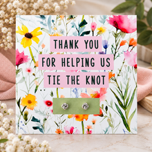 Silver knot earrings. A floral thank-you card with pink text reading 'THANK YOU FOR HELPING US TIE THE KNOT' holding two silver knot stud earrings. Wedding favours 