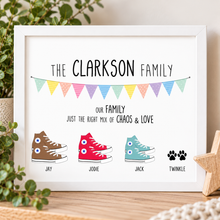 A framed personalised family converse print featuring the text 'THE CLARKSON FAMILY' and 'OUR FAMILY JUST THE RIGHT MIX OF CHAOS & LOVE' above illustrated high-top sneakers and a paw print.