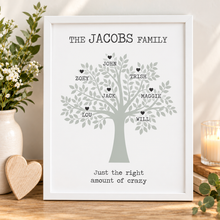 A personalised family tree print. The print reads 'THE JACOBS FAMILY' at the top and 'Just the right amount of crazy' at the bottom, with individual names and small hearts branching from a light grey tree.