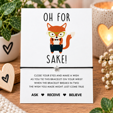 For fox sake wish string bracelet. A white rectangular card with a cartoon fox wearing glasses and a bow tie, reading 'OH FOR FOX SAKE!' and instructions for a wish bracelet.