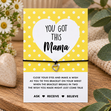 You got this mama wish string bracelet. A yellow and white card with a heart-shaped graphic reading 'YOU GOT THIS Mama' holds a black cord bracelet with a small heart charm.
