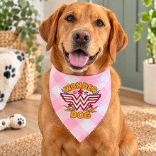 A golden retriever dog wearing a pink plaid bandana with a 'Wonder Dog' graphic. Wonder dog bandana in pink & white gingham print. Superhero dog bandana. Funny slogan dog scarf neck tie