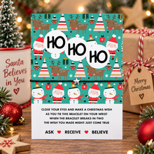 A festive Christmas-themed black cotton cord bracelet with silver star charm with 'HO HO HO' written across the center of the display card. Christmas wish string bracelet. Gift for Christmas eve box.