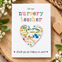 Nursery teacher wildflower seeds gift. A white greeting card with the text 'for my nursery teacher' in multicoloured letters above a removable heart shaped seed paper filled with wildflower seeds and 'Thank you for helping me grow!' at the bottom. Plantable Thank you gift for nursery teacher 