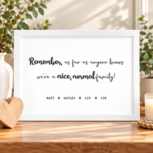 A white framed typographic wall sign on a wooden surface, printed with the phrase “Remember, as far as anyone knows we’re a nice, normal family!” in black script and serif text, with names spaced below. Personalised family print - family Christmas gift 