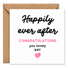 A square white greeting card with a brown kraft envelope behind it. The card reads 'Happily ever after' in black script, 'CONGRATULATIONS' in pink uppercase letters, 'you lovely pair' in black lowercase text, and a small pink heart at the bottom.