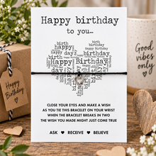 Birthday wish string bracelet. A square white birthday bracelet card with black text and a heart-shaped word cloud, tied with a black cord and a silver heart charm.