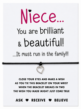 Niece bracelet. A black cord bracelet with a small silver heart charm displayed on a white message card addressed to 'Niece'. The card features pink and black text with instructions and positive well wishes, and the bracelet is shown tied around the center.