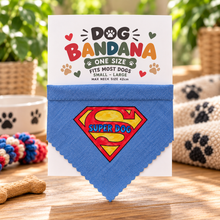 A blue dog bandana with a Superman-style shield graphic reading 'SUPER DOG' is displayed on a white backing card. The card says 'DOG BANDANA ONE SIZE' and includes paw prints and hearts. Super dog bandana in blue yellow and red.. Superhero dog bandana. Funny slogan dog scarf neck tie