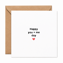 A square white greeting card with the text 'Happy you + me day' in black lowercase letters and a small red heart below, shown with a brown kraft envelope behind it on a white background. First anniversary card. One year married card. Paper anniversary 