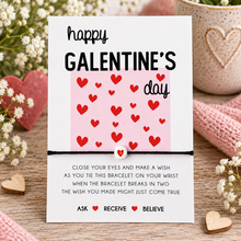 Galentines wish string bracelet. A Galentine's Day themed bracelet set. The card reads 'happy GALENTINE'S day' above a pink panel with red hearts, and below a black string bracelet with a small red heart charm.